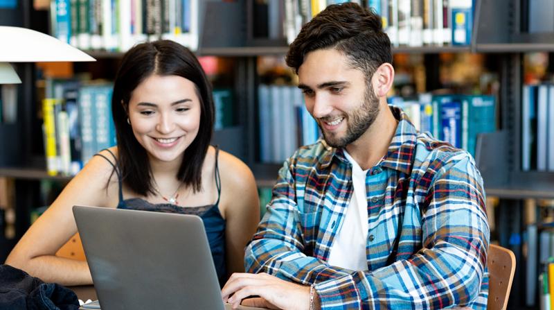 smiling male and female Alamo Colleges students looking at a laptop